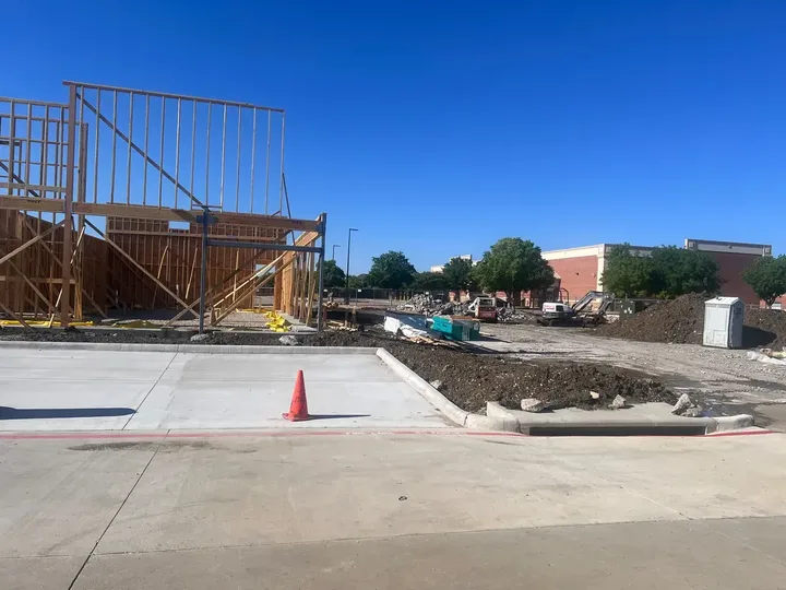 Commercial construction site with wood framing, a new curb and staged materials