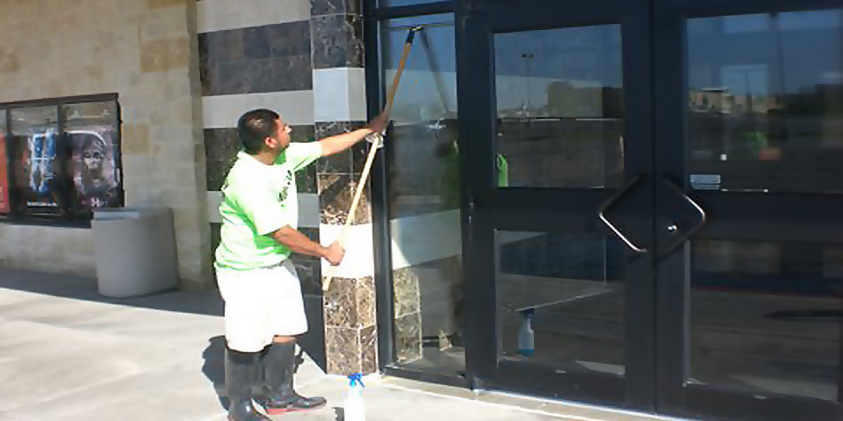 Moore Clean porter squeegeeing storefront glass at an Austin commercial property