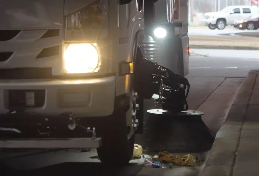 Moore Clean street sweeper broom collecting debris along the curb at night