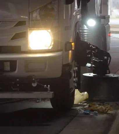 Gutter broom working the curb line on an overnight Austin route